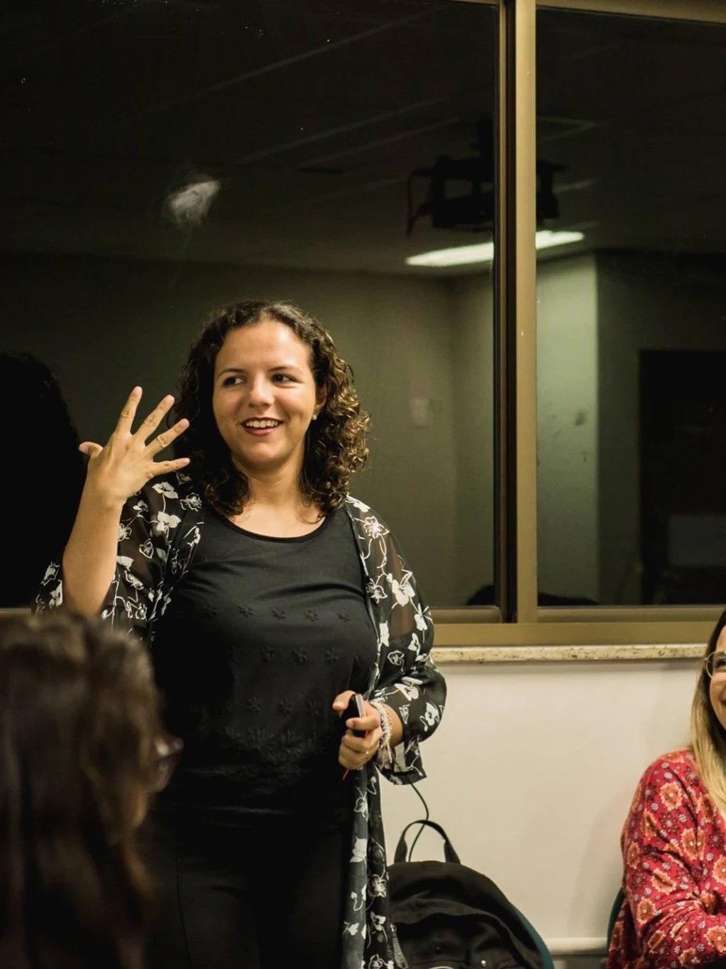 Raquel Camargo mid-explanation during a workshop, participants in the room